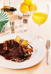 Duck filet with glazed pears on a laid table