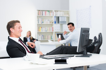 mitarbeiter legt entspannt die beine hoch