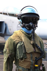 Military jet pilot in full flight gear and helmet with oxygen mask standing near fighter aircraft on airbase runway © Jaroslav Moravcik