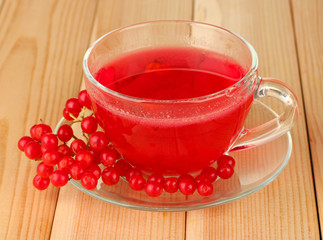 glass cup with broth viburnum on wooden background close-up