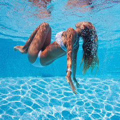 Underwater woman portrait with white bikini in swimming pool.