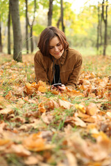 woman lying on a carpet of leaves in autumn park