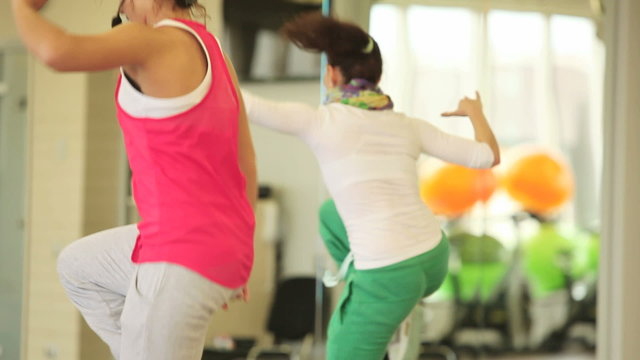 Team of slim women doing exercise on step boards in sport class