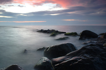 Group of rocks in the water with colorful sky