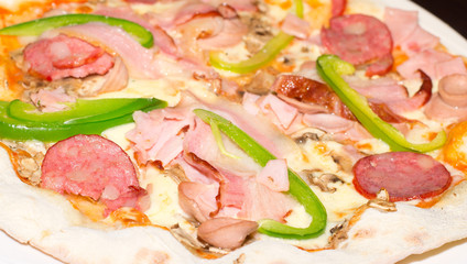 Delicious pizza with ham, peppers, mushrooms and cheese.