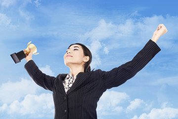 Businesswoman celebrating with trophy in hand