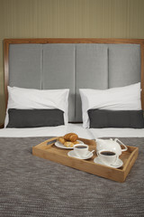 Fototapeta na wymiar Taca z kawy na łóżku w pokoju hotelowym