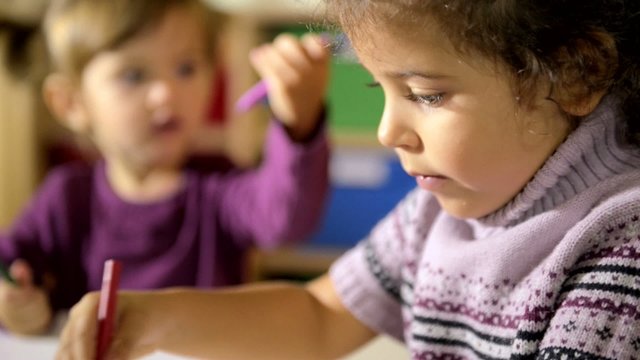 Children and fun, two happy preschoolers drawing in kindergarten