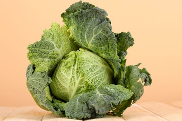 Fresh savoy cabbage on wooden table on beige background