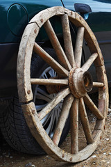 Vintage wagon wheel near the modern car