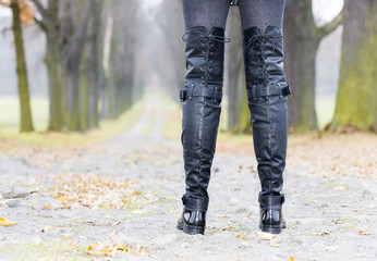 detail of woman wearing black clothes and boots in autumnal alle