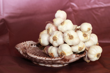 white garlic and lilac onions on a table in a ceramic plate