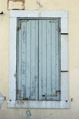 faded light blue grey painted wooden closed shutters in mediteranean doorway