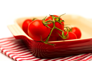 Fresh tomatoes in ceramic dish on white background