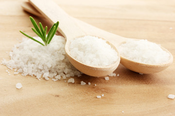 salt in spoons with fresh  rosemary on wooden background