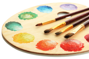 wooden art palette with paint and brushes isolated on white