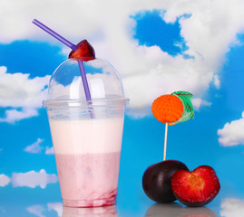 Delicious milk shake with fruit on table on blue sea background