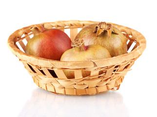 unripe pomegranates in wicker basket isolated on white