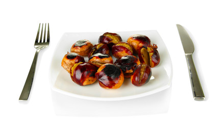 roasted chestnuts in the white plate with fork and knife