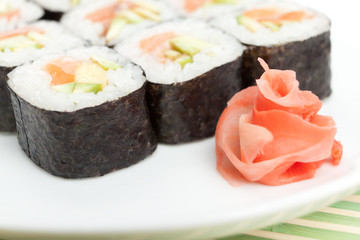 Sushi rolls on the white plate which is on green mat