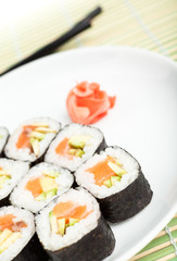 Sushi rolls on the plate with chopsticks on green mat