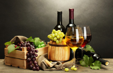 barrel, bottles and glasses of wine and ripe grapes