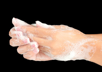 Woman's hands in soapsuds, on black background close-up