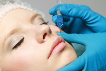Naklejka premium An injection of a botox to a woman's face, close-up