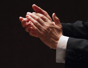 Male hands clapping on black, side-view