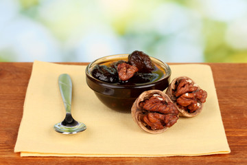 jam  walnuts in a bowl on a table on a green background