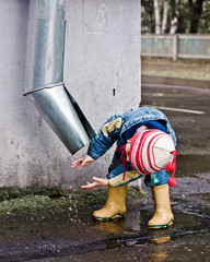 Kid washing hands under a water pipe.