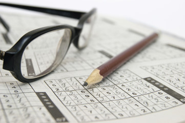 Pencil and glasses on a sudoku game