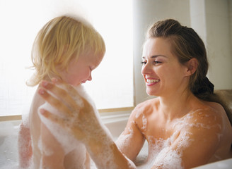 Mother washing with baby in bathtub © Alliance