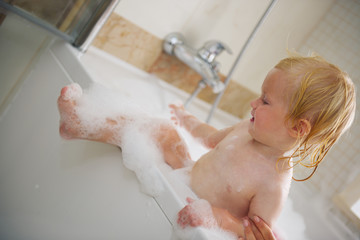 Fototapeta premium Baby trying to get out from bathtub