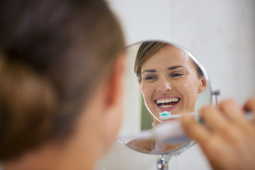 Happy woman brushing teeth with electric toothbrush