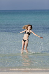 Frau mit Bikini springt im meer hochformat