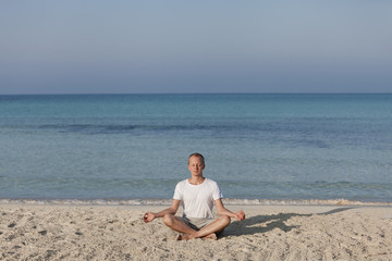 Fototapeta na wymiar Mann macht yoga Sport am Strand Querformat