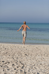 Fototapeta na wymiar mann rennt am strand im Wasser Hochformat