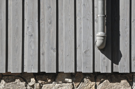 Wooden facade, rubble masonry and downpipe