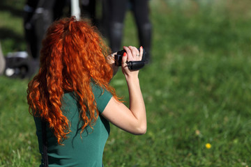 Kobieta z rudymi włosami kręci film kamerą amatorską, czerwona. - obrazy, fototapety, plakaty
