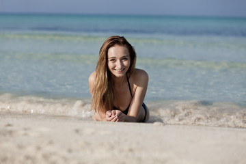 Fototapeta na wymiar Junge Frau mit schwarzem Bikini am Strand im Wasser Querformat