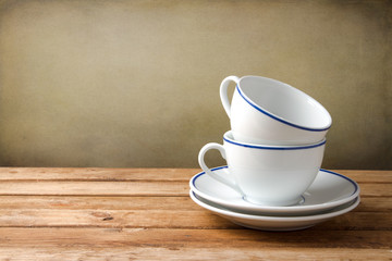 Two coffee cups on wooden tabletop against grunge background