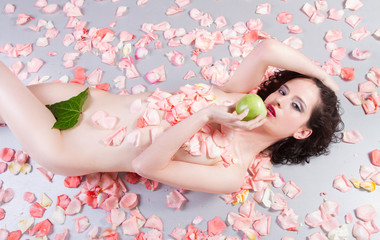 Obraz na płótnie Canvas nude woman with roses eating a green apple