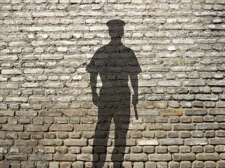 ombre de policier sur mur de briques