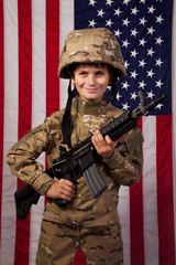 Boy USA soldier in front of American flag with rifle