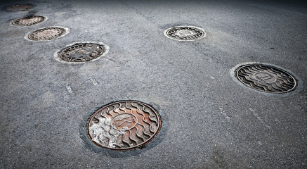 Round manholes on the asphalt road in the city