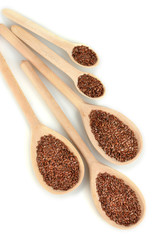 flax seeds in wooden spoons on white background close-up