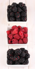 Ripe raspberries and brambles on wooden table