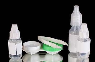 Eye drops and lenses on black background