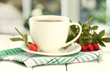 cup of tea with hip roses, on wooden table